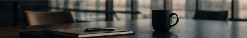 Meeting table with notebook, pen and coffee